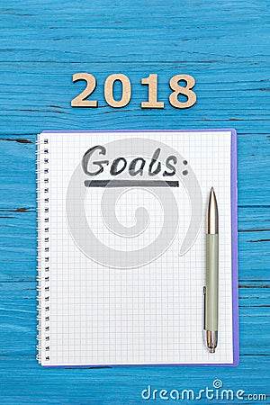 Notebook with new years goals for 2018 with a pen and numbers 2018 on a blue wooden table Stock Photo