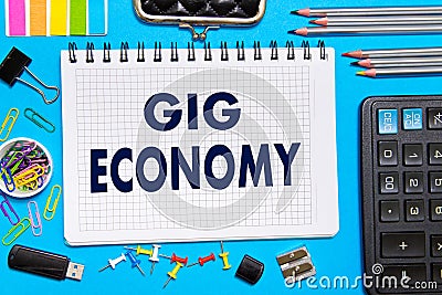 Notebook with Notes GIG ECONOMY office tools on a blue background . Concept GIG ECONOMY Stock Photo