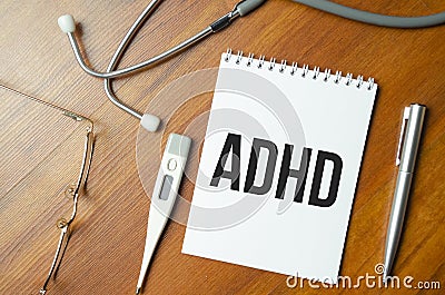 Notebook page with text ADHD - Attention Deficit Hyperactivity Disorder, on a table with a stethoscope and pen, medical concept Stock Photo