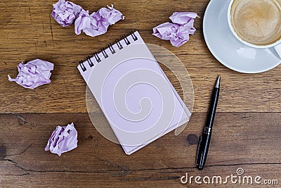 Notebook with pen aside coffee crumpled paper on wooden table Stock Photo