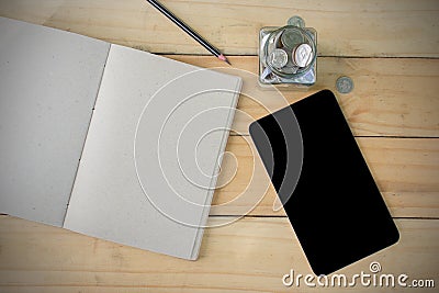 Notebook, Pen, Tablet, Stack Coins on wooden table form top view. Stock Photo