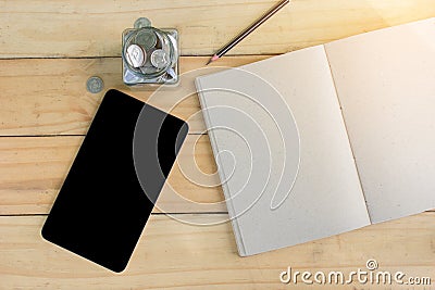 Notebook, Pen, Tablet, Stack Coins on wooden table form top view. Stock Photo