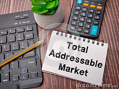 Notebook and pencil with the word Total Addressable Market Stock Photo