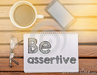 Notebook on table with text about soft competence: Be assertive Stock Photo