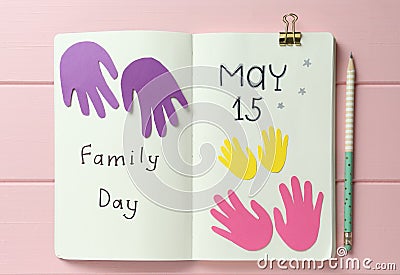 Notebook with text Family Day May 15 and paper cutouts on pink wooden table, flat lay Stock Photo