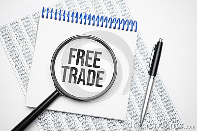 In the notebook is the text of free, trade, trading, , next to the black pen, magnifying glass. A business concept Stock Photo