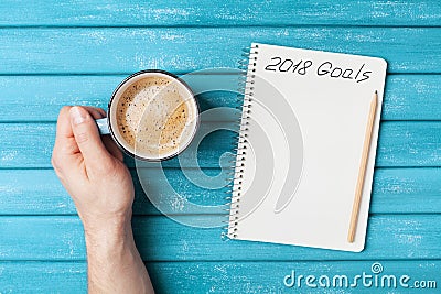 Notebook with text 2018 goals and cup of coffee on wooden desk top view. Planning and business concept. New year resolution. Stock Photo