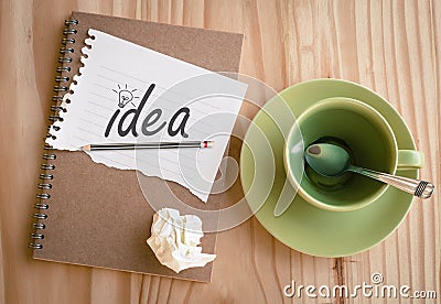 Notebook with text inside Idea and light bulb on table Stock Photo