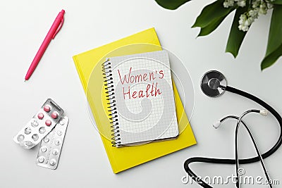 Notebook with text Women`s Health, pills and stethoscope on white table, flat lay Stock Photo