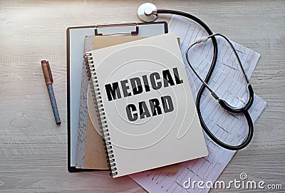 On the notebook there is an inscription on a medical theme. Top view of a notebook with medical records and a stethoscope. Stock Photo