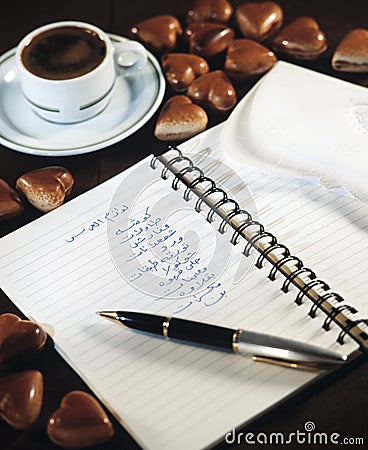 Notebook with wedding party shopping list beside a cup of coffee and chocolate hearts still life Stock Photo