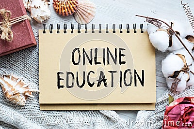 A notebook with the words ONLINE EDUCATION on a light table along with a cotton branch and a vintage gift box. There are Stock Photo