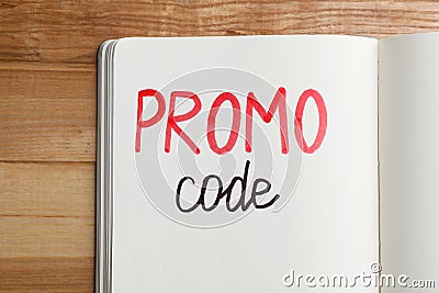 Notebook with words Promo Code on wooden table, top view Stock Photo