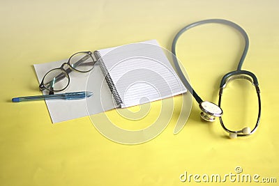 Notebooks and pens placed on a yellow background with medical headsets Working concepts Stock Photo