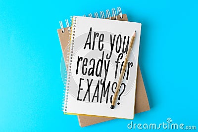 Notebooks with phrase ARE YOU READY FOR EXAMS and pencil on light blue background Stock Photo