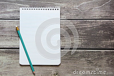 Notepad with a blank white sheet in a checker paper with simple graphite pencil lies on the background of wooden boards Stock Photo