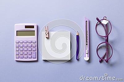 Notepad, colored pencil, cutter, calculator, glasses on purple background Stock Photo