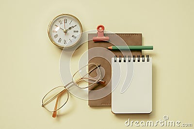 Notepad, diary, clock, eyeglasses, pencil, clip on yellow desk background. flay lay, top view, copy space Stock Photo