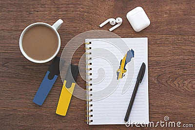 notepad with flag of sweden, wireless headphones, coffee cup, pen, markers on brown table, Stock Photo