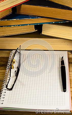 Notepad, fountain pen and glasses in front of books Stock Photo