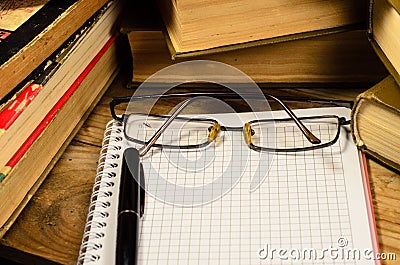 Notepad, fountain pen and glasses in front of books Stock Photo