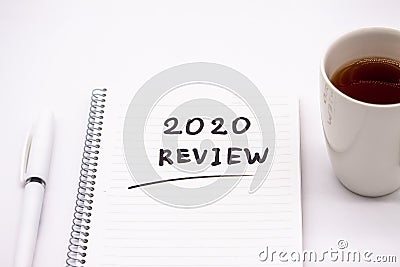 Notepad inscribed 2020 review with pen and tea cup on a white background Stock Photo