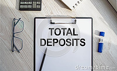 Notepad with the inscription TOTAL DEPOSITS. Conceptual image, business accessories, calculator isolated on the desktop. Finance Stock Photo