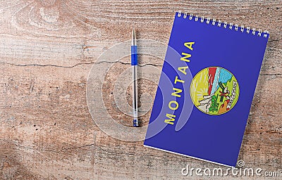 Notepad with Montana flag, pen on wooden background Stock Photo