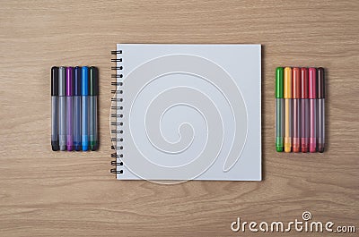 Notepad or notebook with Many colorful pens on brown wood table.using for education, business background Stock Photo