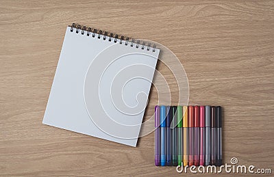 Notepad or notebook with Many colorful pens on brown wood table.using for education, business background Stock Photo