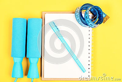 Notepad, pen and gym equipment top view on yellow background Stock Photo