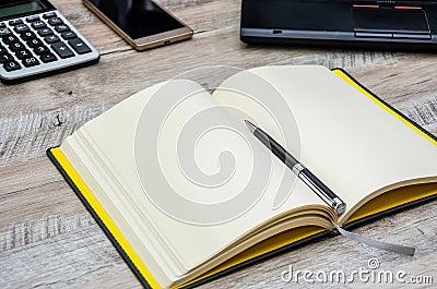 Notepad, pen, smartphone and part of the laptop on a wooden background Stock Photo