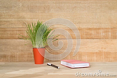 Notepad and pen on the wooden table. Green houseplant. Begining of the work day Stock Photo