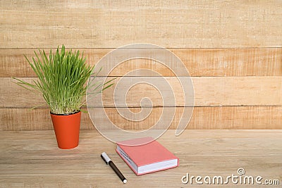 Notepad and pen on the wooden table. Green houseplant. Begining of the work day Stock Photo