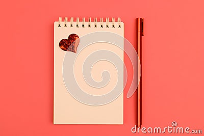 Notepad, red pen and heart on coral background Stock Photo