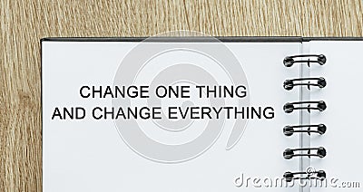 Notepad with text Change one thing and change everything on wooden deskt. Business and finance concept Stock Photo