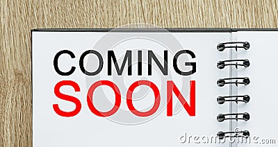 Notepad with text COMING SOON on wooden deskt. Business and finance concept Stock Photo