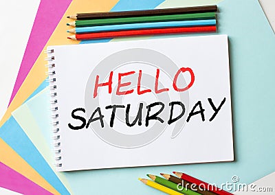 The Notepad with the text Hello Saturday is on colored paper with color pencils Stock Photo