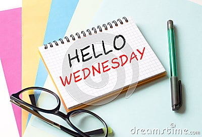 The Notepad with the text Hello Wednesday is on colored paper with glasses and a pen Stock Photo