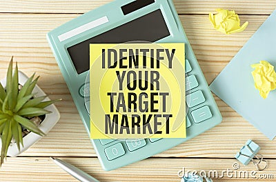 with the text Identify Your Target Market on an office table with pencils, paper clips and a flower Stock Photo