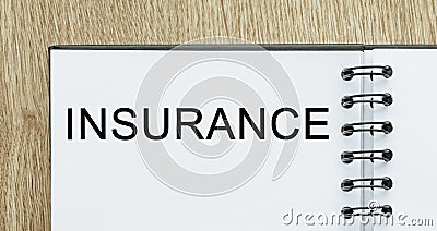 Notepad with text INSURANCE on wooden deskt. Business and finance concept Stock Photo