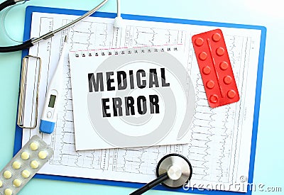 A notepad with the text MEDICAL ERROR lies on a medical clipboard with a stethoscope and pills on a blue background. Stock Photo
