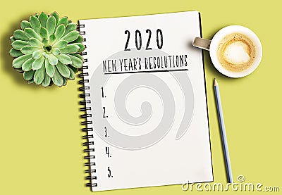 Notepad with text 2020 New Years Resolutions and numbered list on yellow desk with succulent plant and cup of coffee Stock Photo