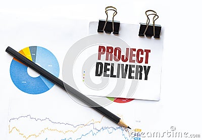 Notepad with text PROJECT DELIVERY on business charts and pen Stock Photo