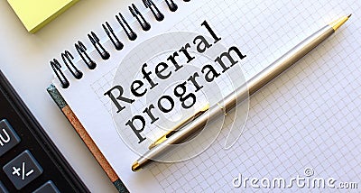 Notepad with text REFERRAL PROGRAM, next to it lies a calculator and yellow note papers Stock Photo