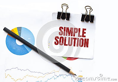Notepad with text SIMPLE SOLUTION on business charts and pen Stock Photo