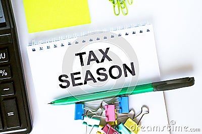 Notepad with text Tax Season. Calculator, green pen stickers and stationary clips Stock Photo