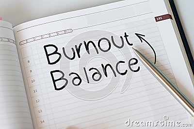 notepad with text written BURNOUT AND BALANCE, concept of a hardworking worker trying to avoid burnout and finding a balance to Stock Photo
