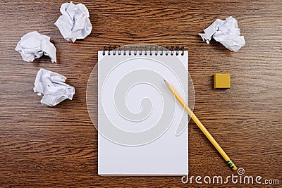 Notepad on a wooden table and crumpled sheets around. Flat lay. Stock Photo