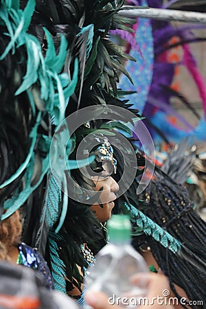 NOTTING HILL, LONDON - AUGUST 27, 2018: Notting Hill Carnival, side-on view of woman wearing large feathery headpiece in the parad Editorial Stock Photo